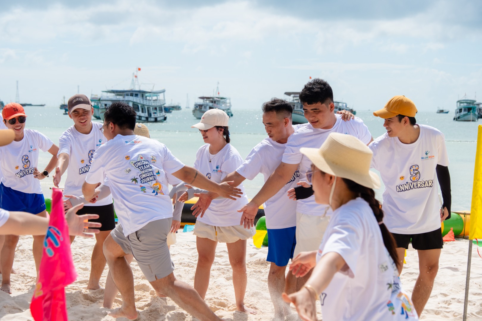 Cả đội nối thành hàng dài trên bãi cát, tay ôm vai nhau